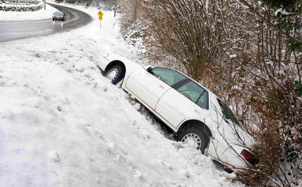 White car slid off a snowy road into a ditch